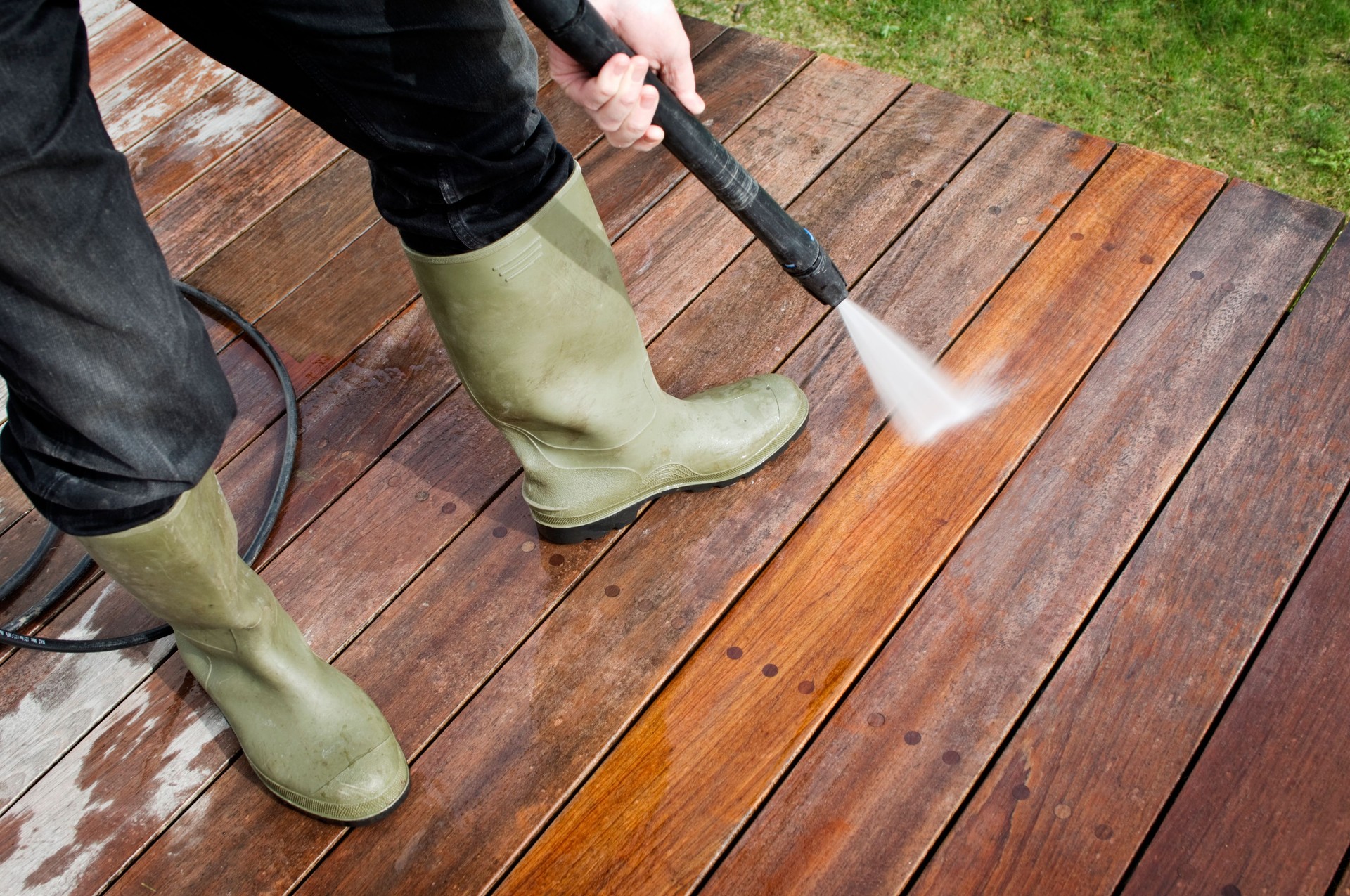 Man Cleaning Patio Decking With a Pressure Hose
